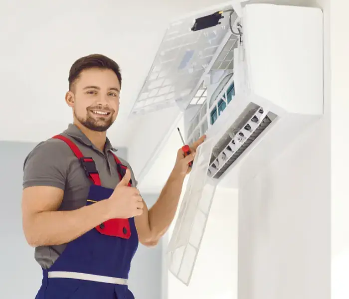 Air conditioning installer in Manchester Smiling engineer fitting a wall-mounted air conditioning unit